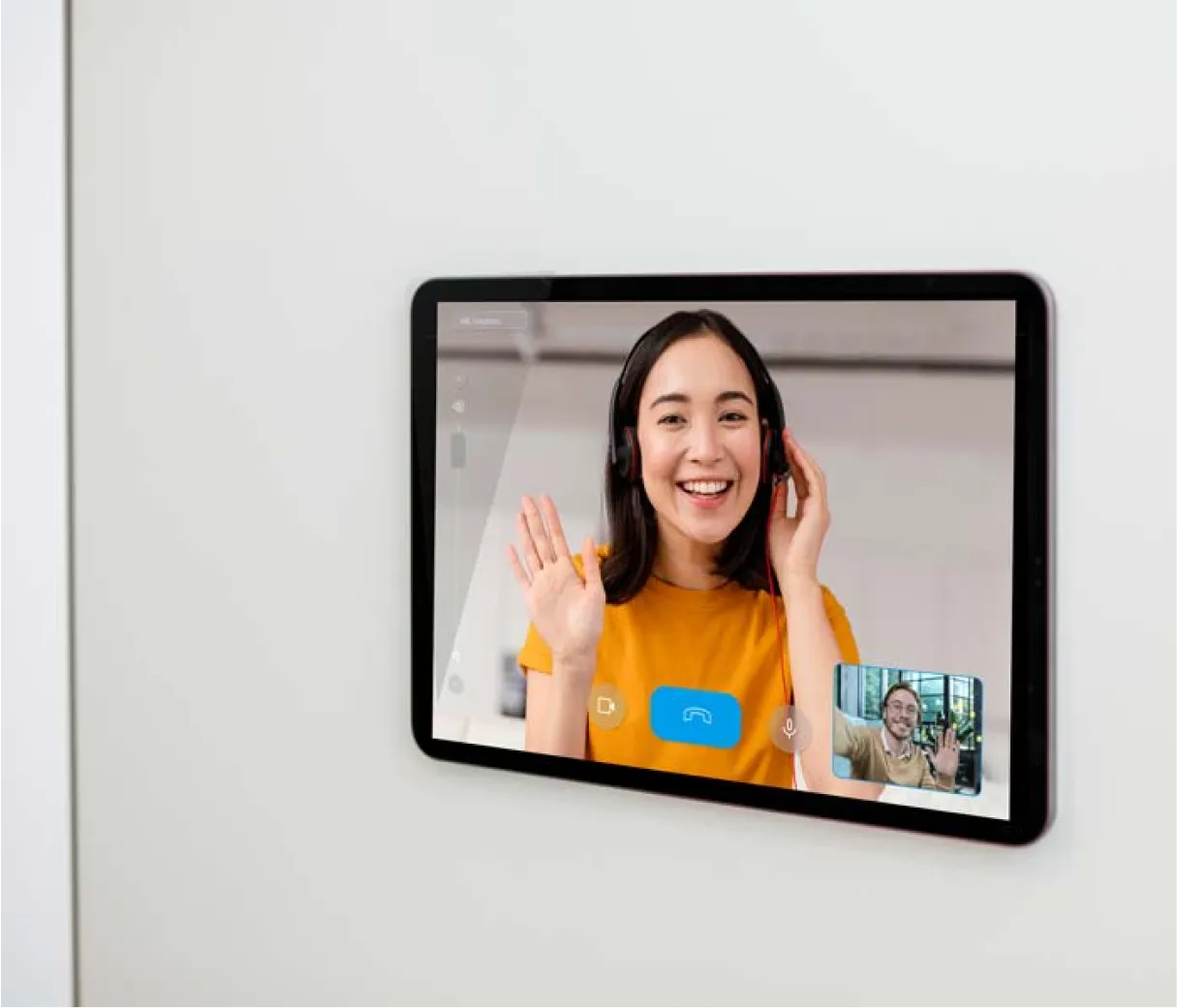 A wall-mounted tablet showing a video call with a smiling receptionist